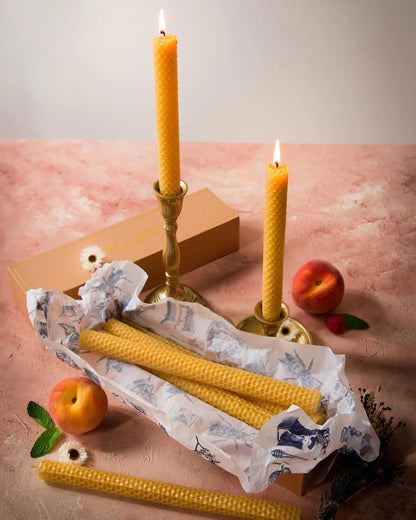 Bougies Lucienne en cire d'abeille gaufrée présentées dans leur boîte avec deux chandelles allumées.