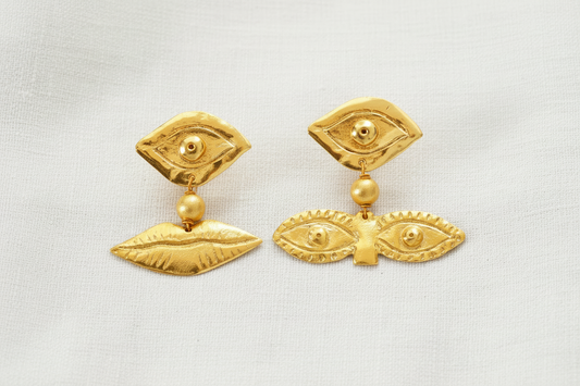 Boucles d'oreilles asymétriques en laiton plaqué or avec motifs d'yeux et de lèvres.