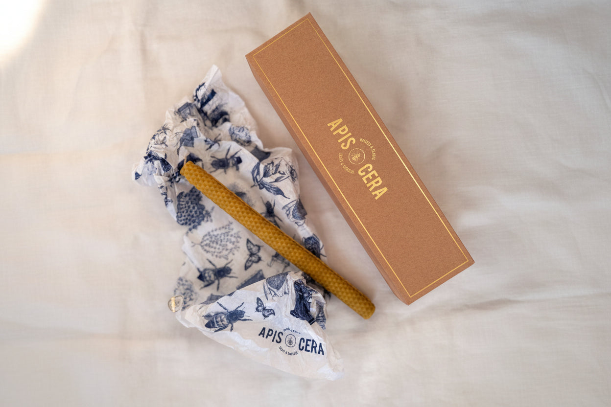 Une bougie Lucienne en cire d'abeille gaufrée à côté de son emballage illustré et de sa boîte.