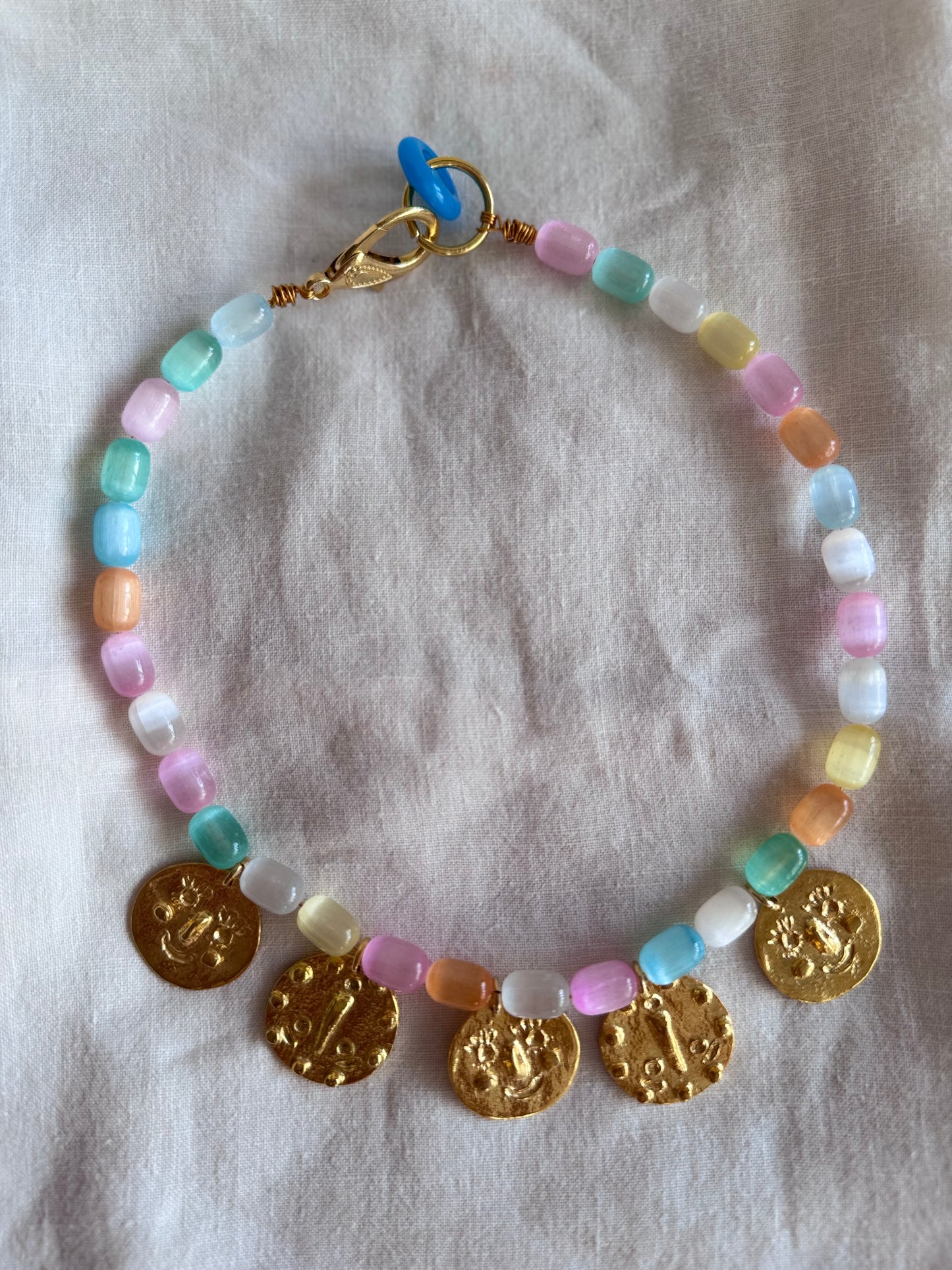 Détail collier five in a row – pendentifs dorés alignés